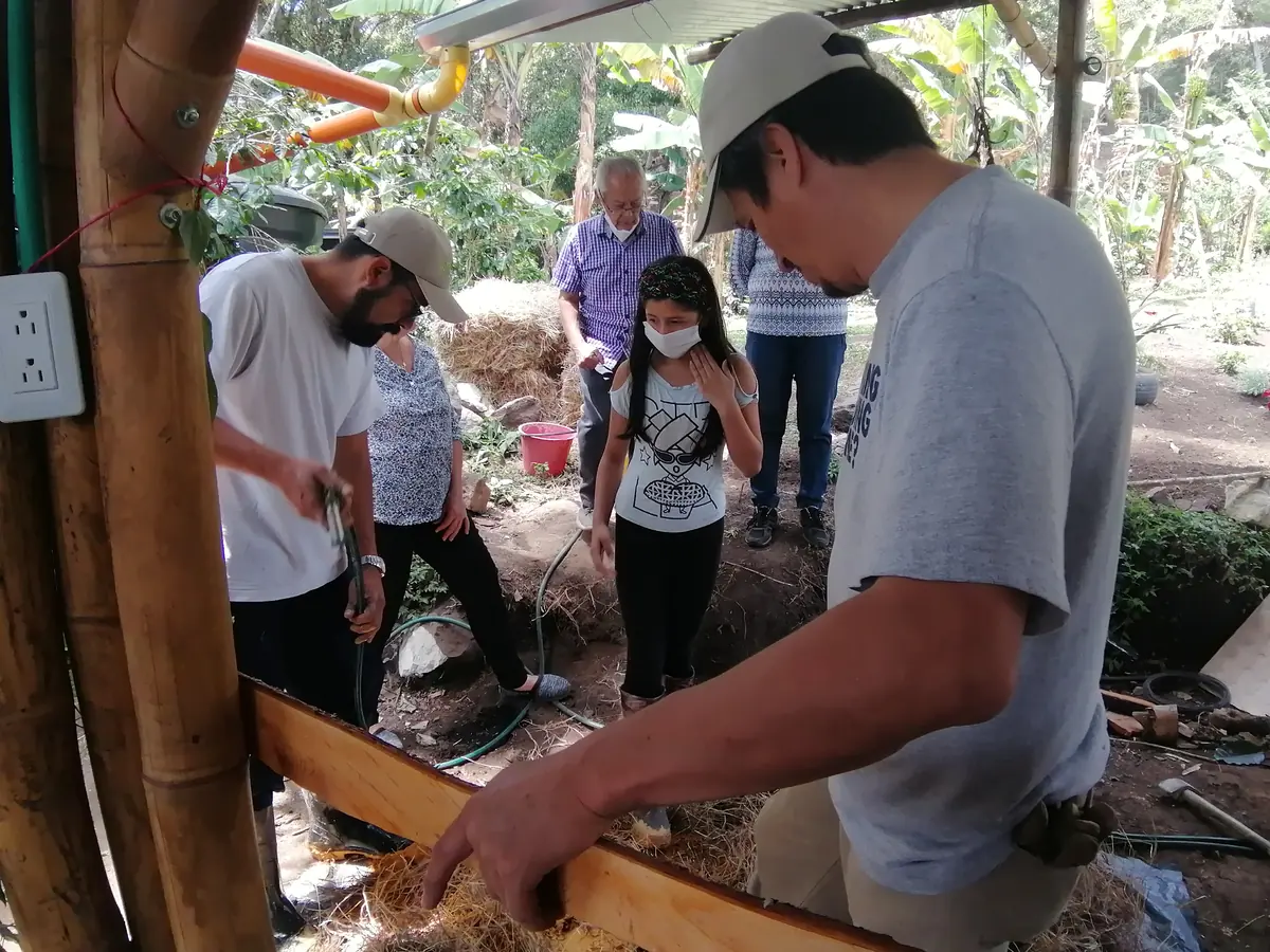 Personas construyendo un muro con barro y guadua